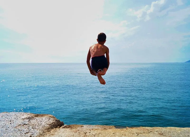 Young boy jumping into the sea.