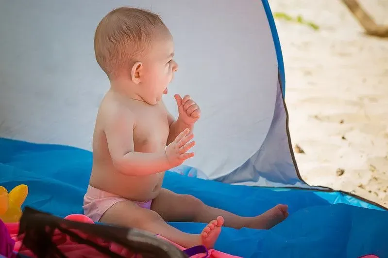 Small baby sitting in a beach tent