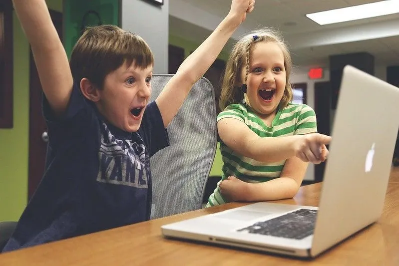 Young boy and girl looking at the computer laughing and cheering.