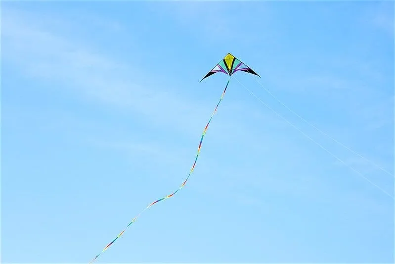 A multi-coloured kite flying high in a blue sky.