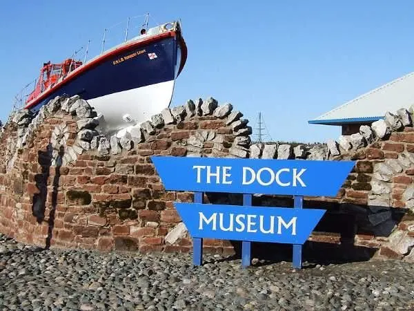 Entrance to the Dock Museum, Cumbria. There is a boat seemingly docked by the wall.