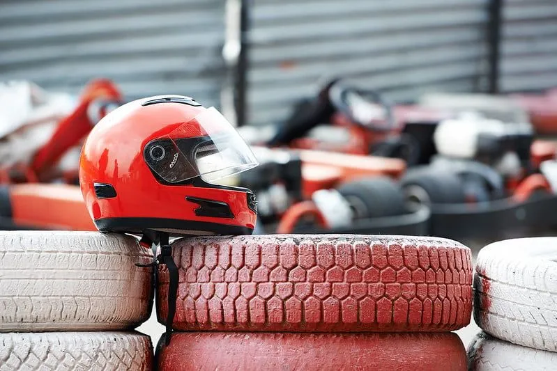 A red helmet on top of a stack of red tyres at the go karting track.