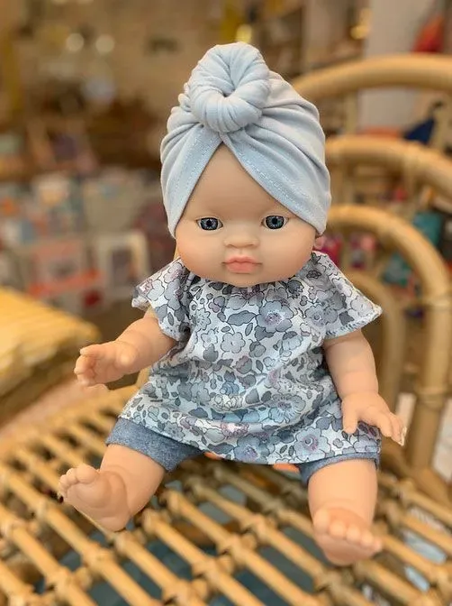 A Paola Reina Doll With Clothes sitting on the table.