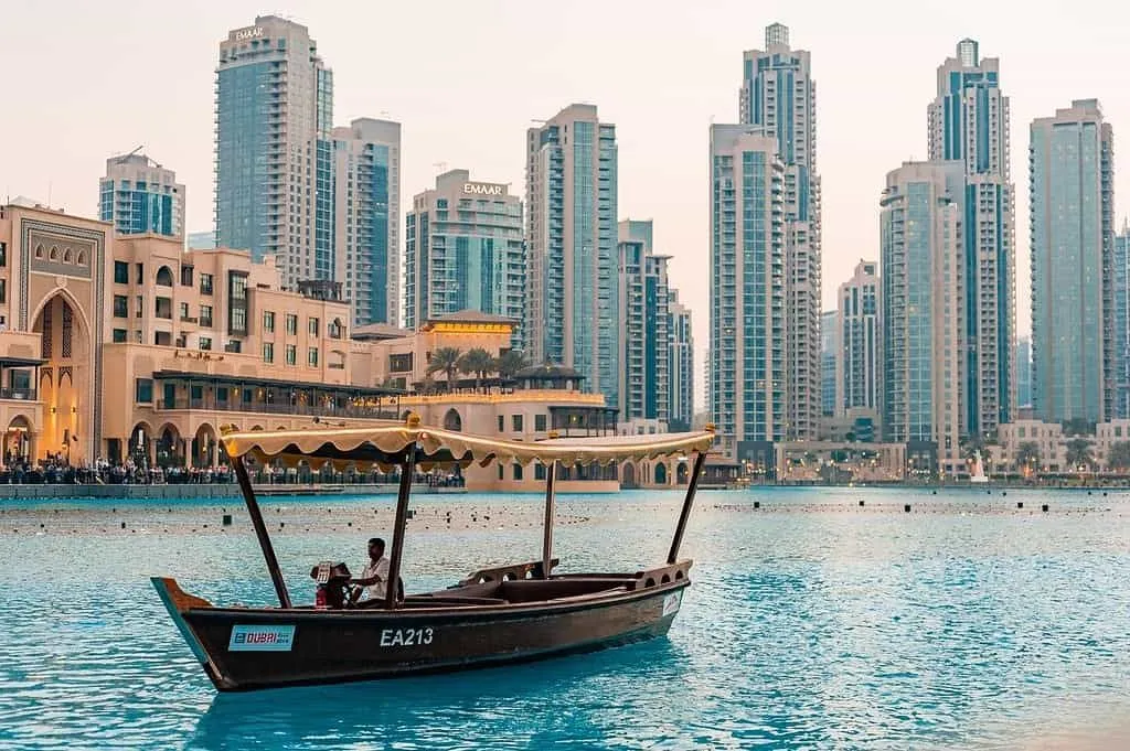 A boat on the water in downtown Dubai city, surrounded by high-rise buildings.