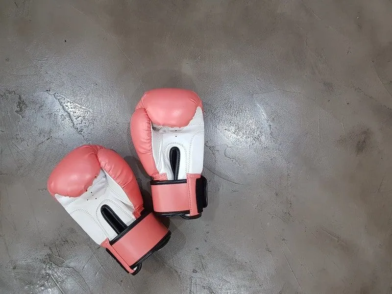 Pair of pink and white boxing gloves on the floor in the training studio.