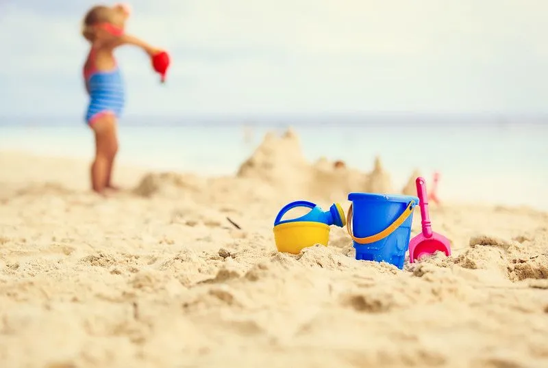 girl building sandcastles on the beach with her sand toys