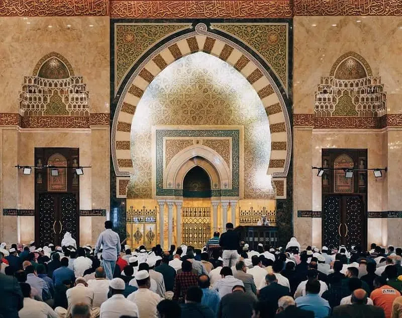 Inside an ornately decorated mosque, men are doing Ramadan prayers.