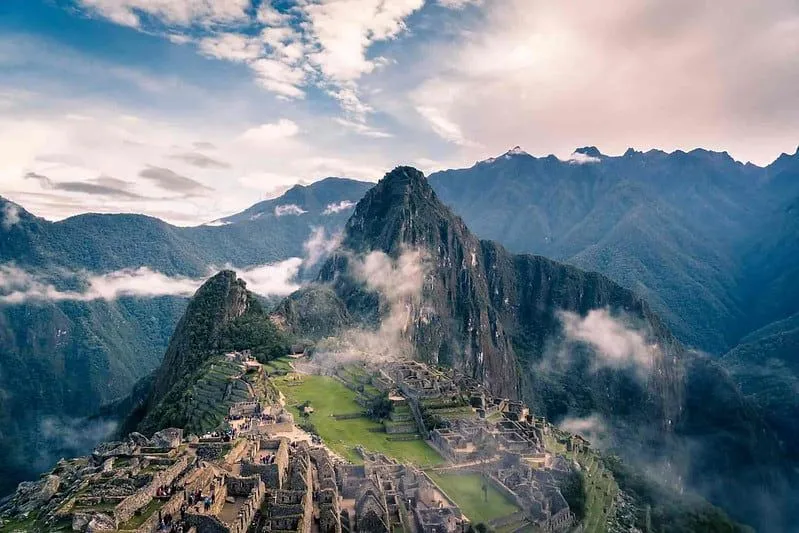 A view from above of Machu Picchu with the sun setting behind.