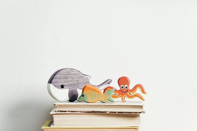 Figurines of a whale, a fish and an octopus on top of a pile of books.