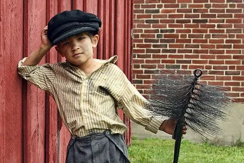 A young Victorian chimney sweep boy covered in soot.