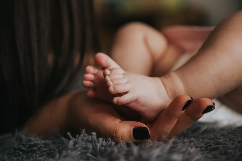 Newborn baby's feet resting in new mum's hand.