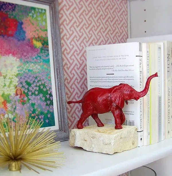 Bookend with a red elephant with its trunk in the air on it.