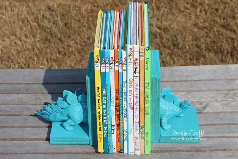 Bookends made with half of a blue toy dinosaur on each side of the books.