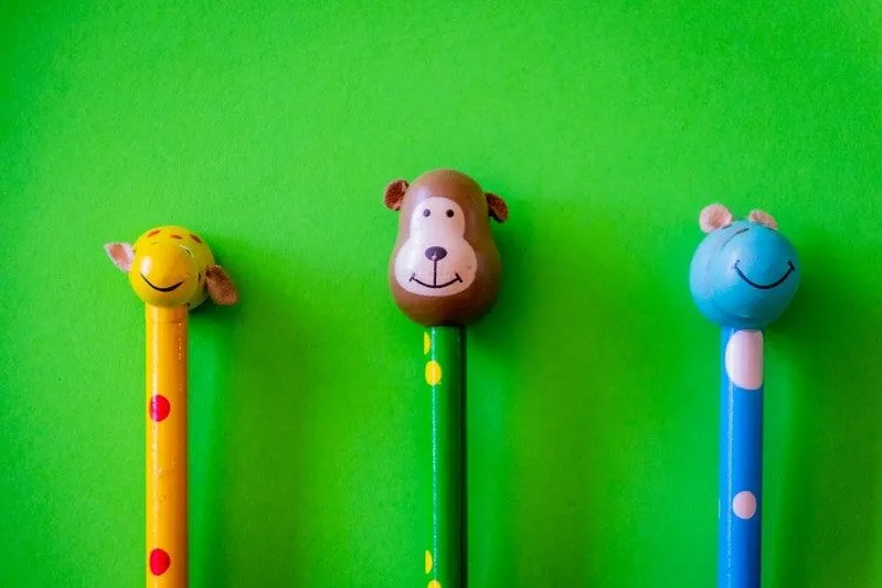 Three pencils with animal head figurines on the top (a giraffe, a monkey and a mouse).