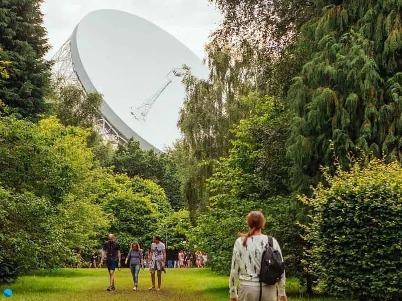 The Lovell telescope visible through the trees at Jodrell Bank Discovery Centre.