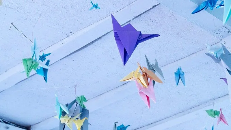 Different coloured origami ducks hanging from the ceiling.