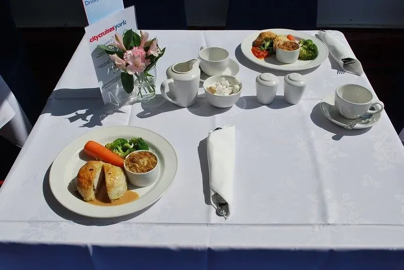 Two plates of chicken and ham hock wellington and potato and leek gratin on a white tablecloth. 