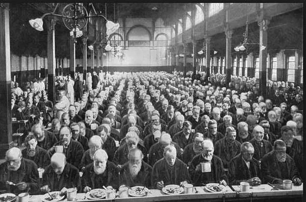 Rows and row of men in a black and white photograph of a Victorian workhouse. 