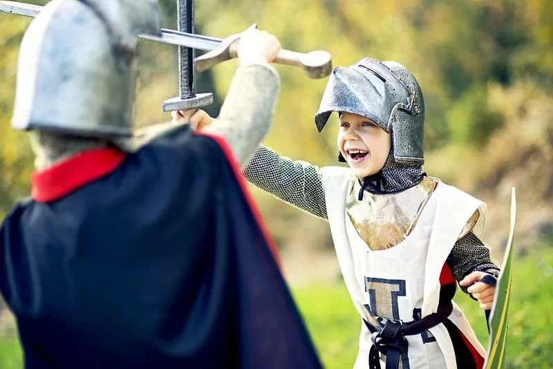 Young boys dressed as Anglo-Saxon knights, having a pretend duel.