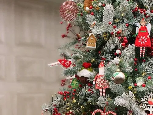 A close up of a frosted Christmas tree with lots of traditional decorations and baubles hanging on it.