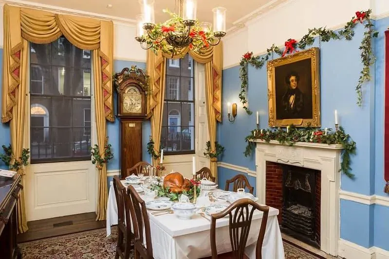 A Victorian dining room adorned with Christmas decorations and a feast, including roast turkey, on the table.