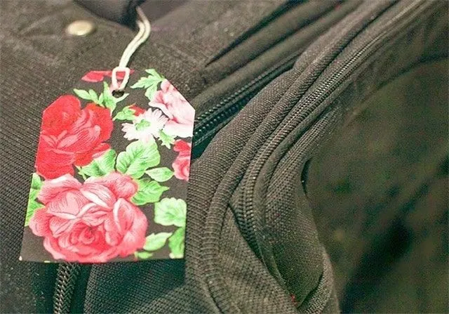 Paper DIY luggage tag in a floral print, tied onto a suicase.