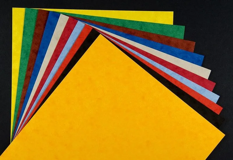 A pile of coloured, textured card fanned out against a black background.