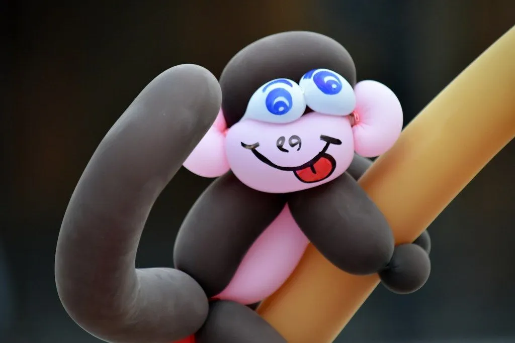 Balloon monkey made from pink and black balloons, with a silly face drawn on.