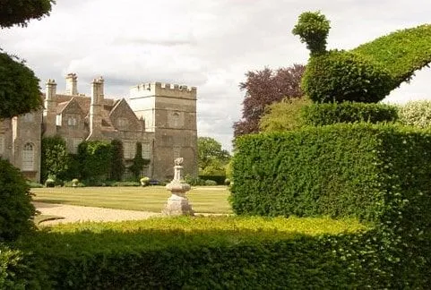 View of Grimsthorpe Castle from its gardens with tall hedges.