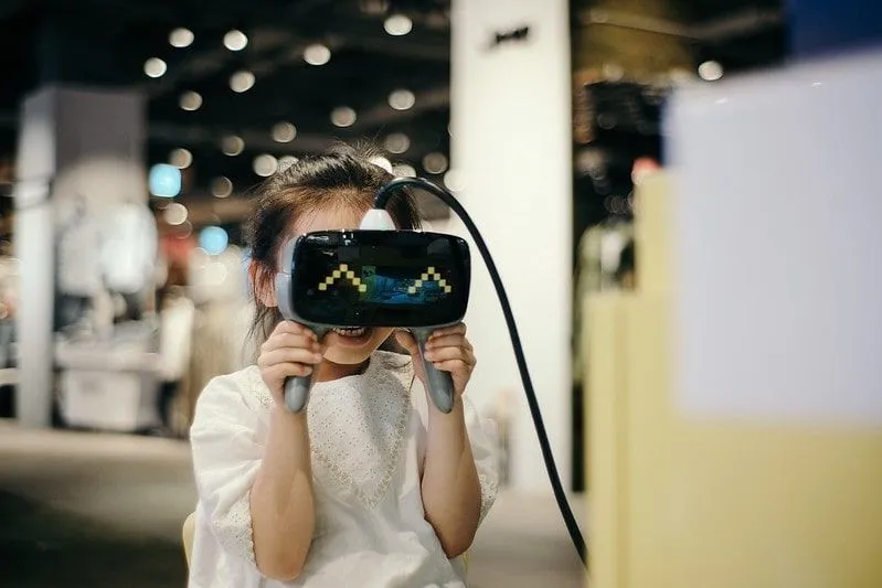 Little girl holding the VR headset to her eyes, smiling.
