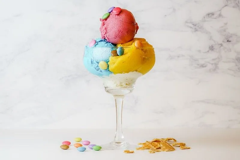 Ice cream sundae with three colourful scoops and smarties on top.
