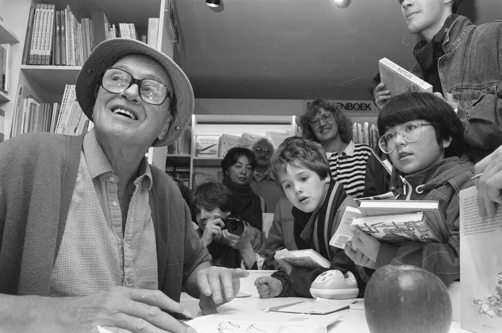 Black and white photograph of Roald Dahl signing books for children.