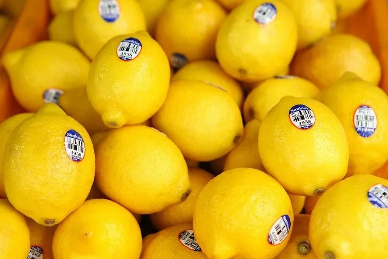Crate of bright yellow lemons with stickers on.
