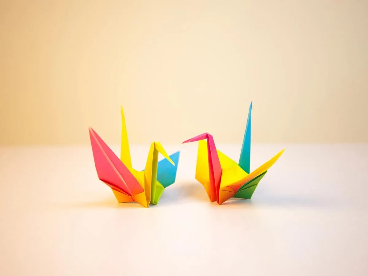 Two multi-coloured origami birds on a table.