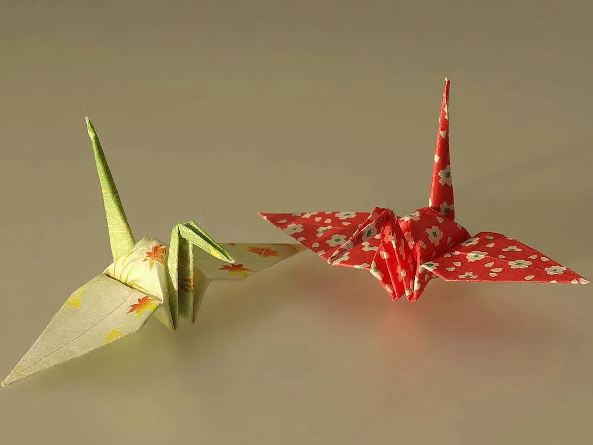 A yellow patterned origami swan and a red patterned origami swan.