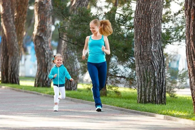 Mum and young daughter running together in the park.