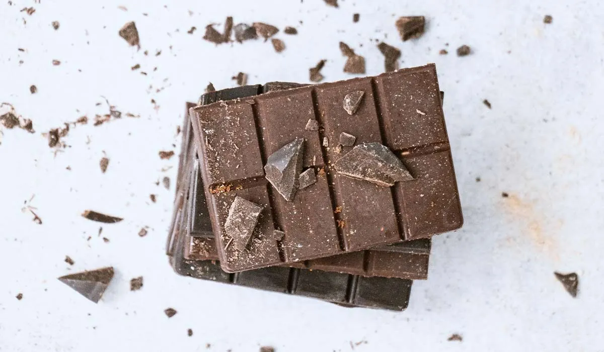 Stack of raw chocolate with shavings and crumbs all around it.