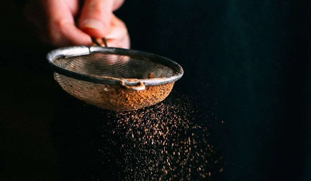 Someone dusting cocoa powder with a sieve.