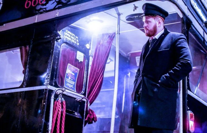 An old-fashioned conductor waiting at the entrance to a Ghost Tour Bus.