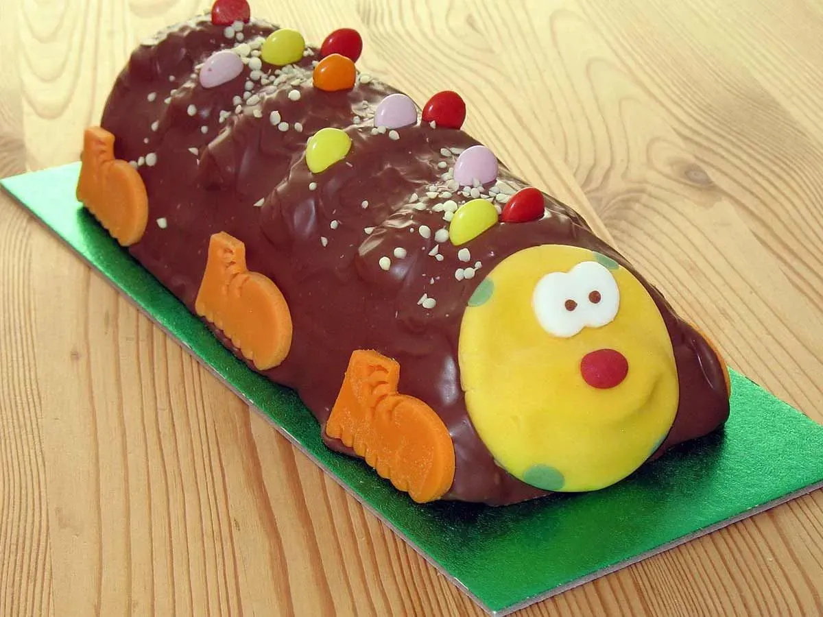 Chocolate caterpillar birthday cake on a green cake board.