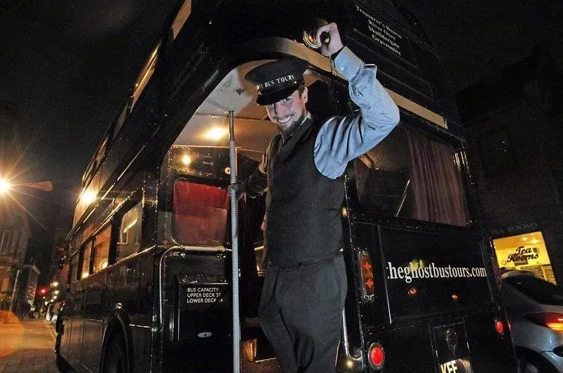 An actor guide tipping his hat at the camera at the entrance to the Ghost Bus Tour York.
