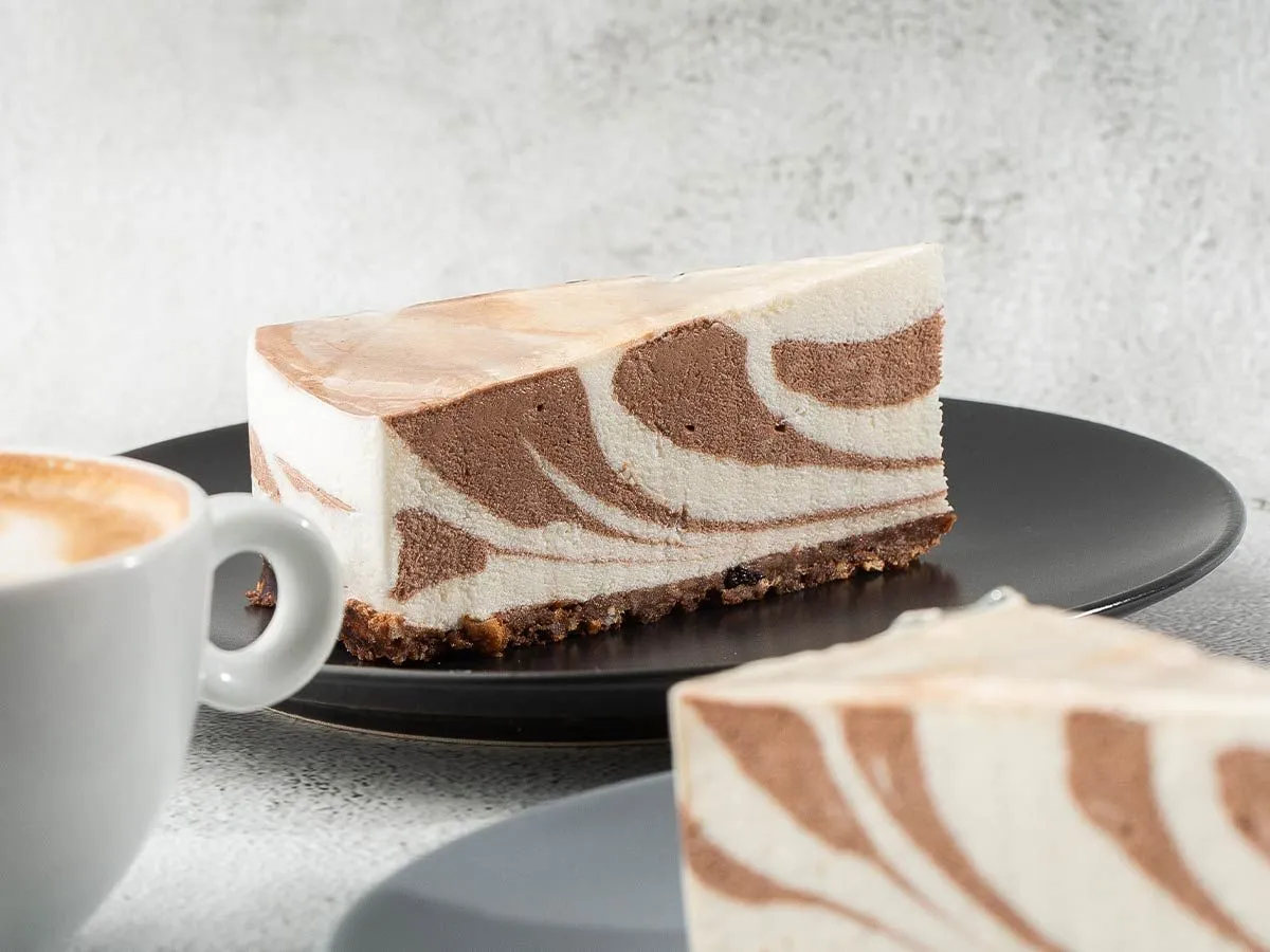 A slice of zebra cake on a plate and a mug of coffee.