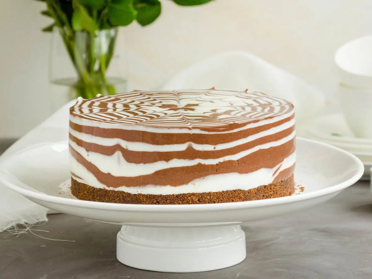 A whole zebra cake, the vanilla and chocolate swirled together, on a white plate.