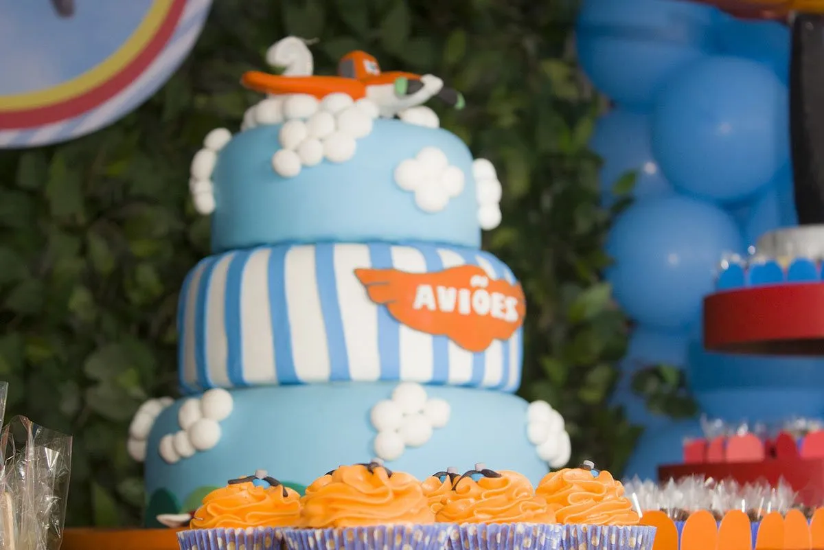 Three-tiered blue cake with an orange airplane on top.