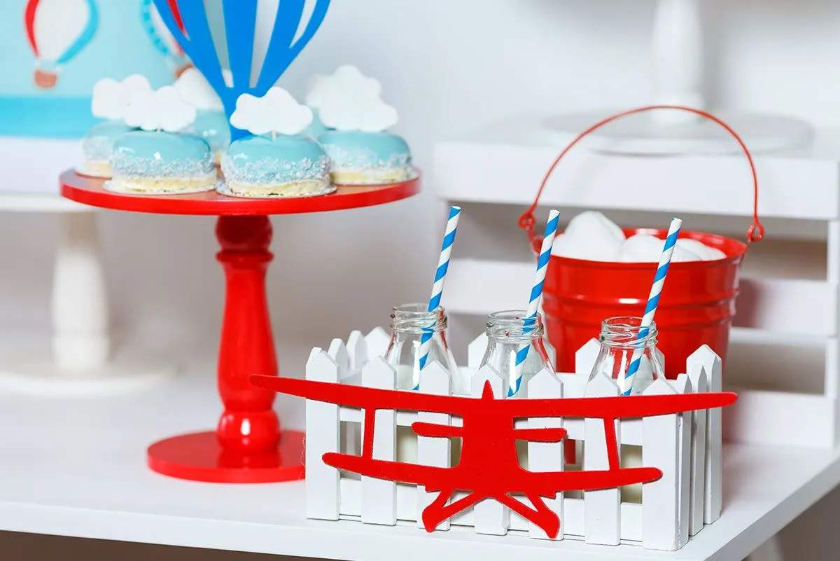 Platter of blue, sky-themed cakes and red airplane decorations around the table.