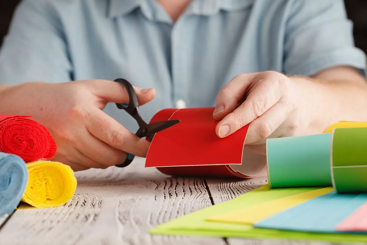 Close up of someone cutting a piece of red card to make a DIY chore chart.