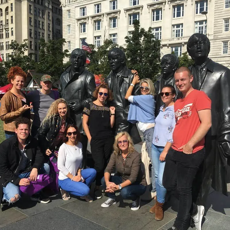 People posing with statues of The Beatles in Liverpool.