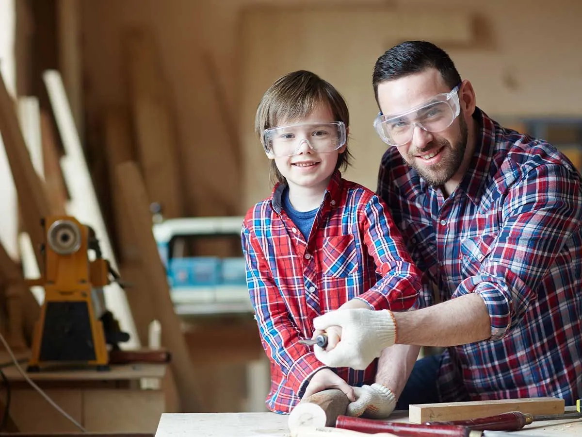 Father and son making a bird box together: they are smiling with the materials they need.