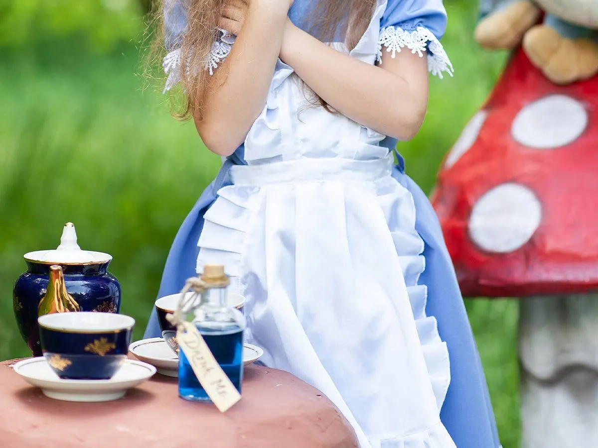 Girl dressed as Alice in Wonderland acting out the Madhatter's tea party.