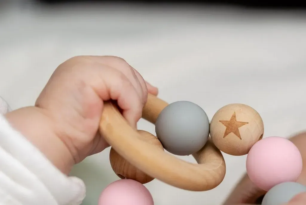Babys hand holding a wooden ring toy